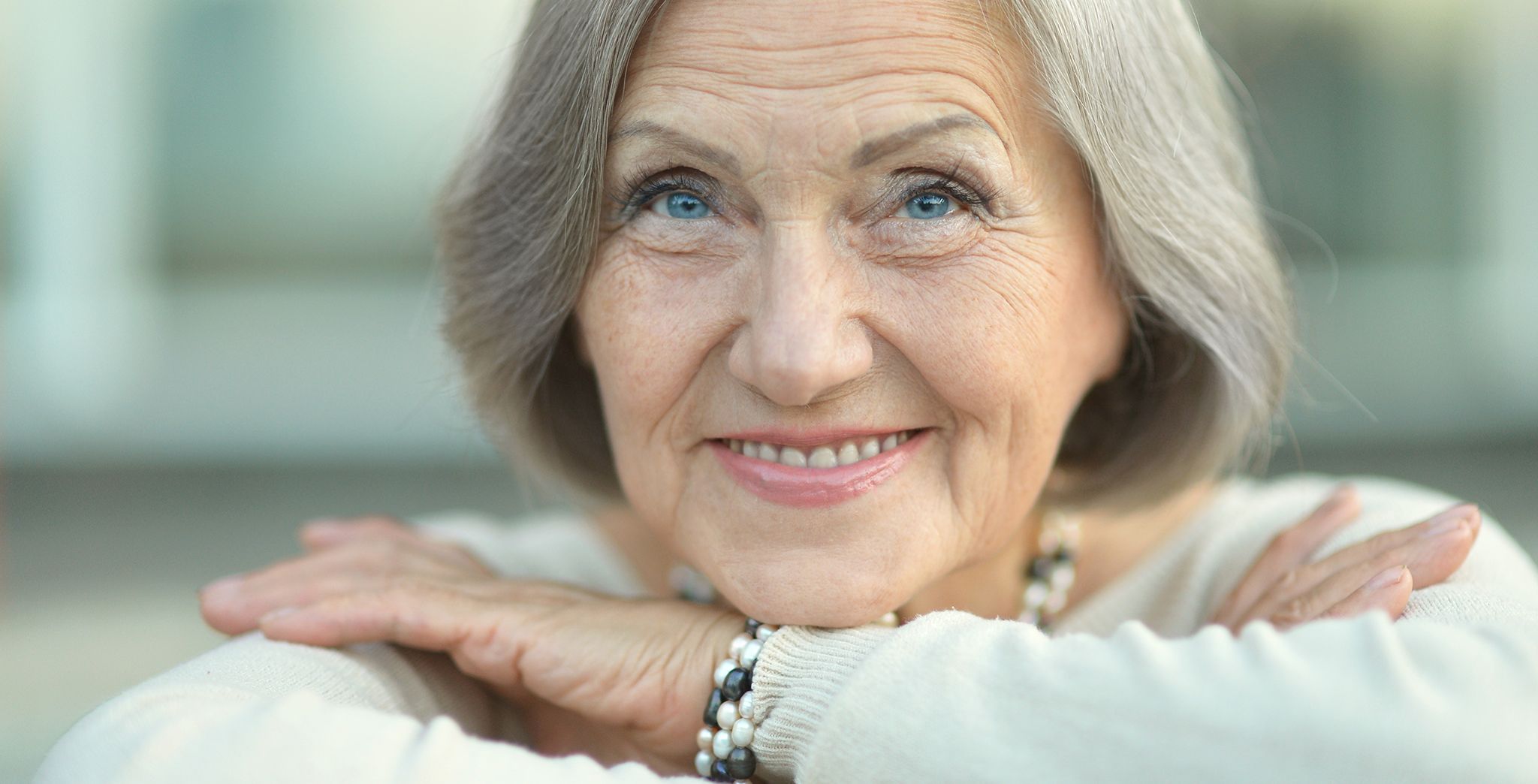Close up of a senior woman smiling with her head resting on crossed arms